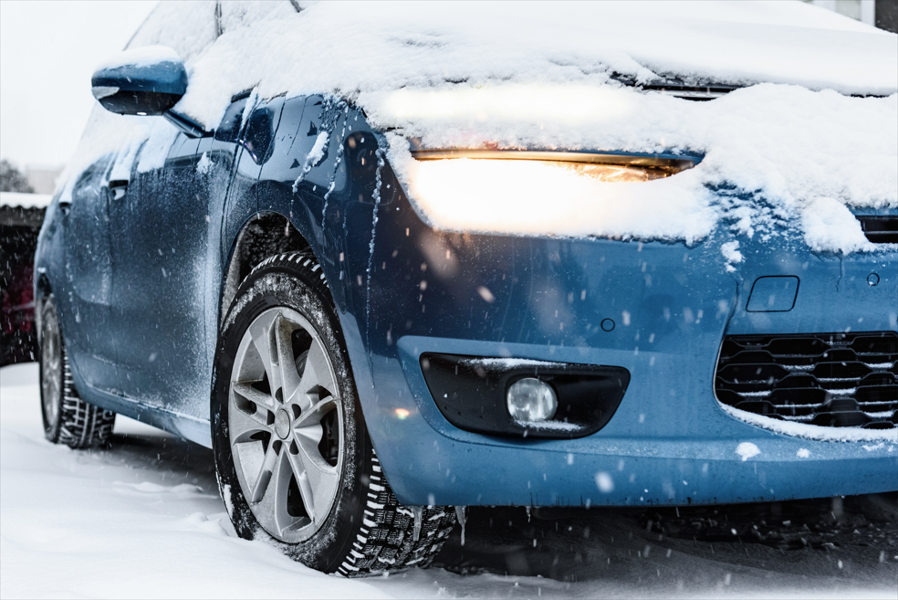 blue car with paint protection film covered in snow